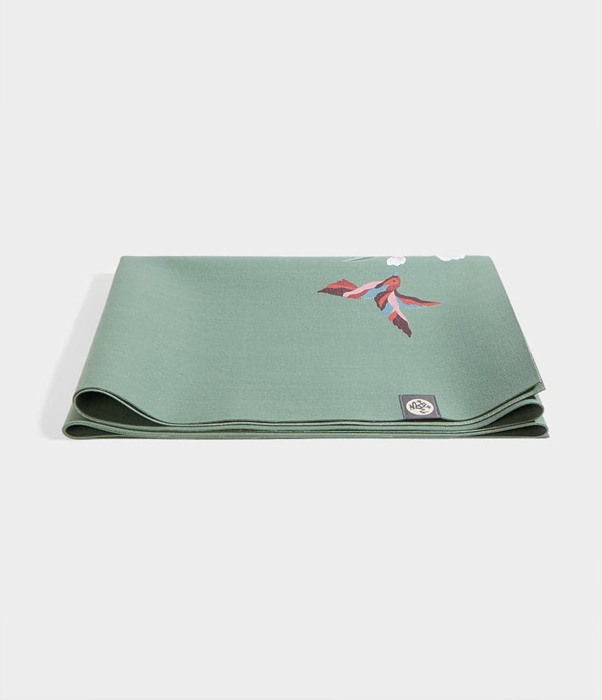Manduka eKO SuperLite travel mat shown rolled beside its textured natural-rubber surface